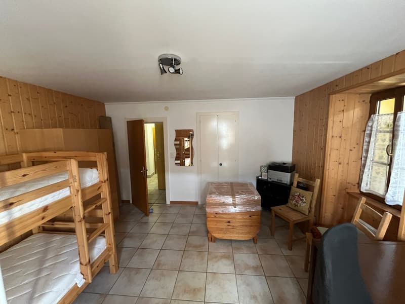 room with wooden walls, wooden bunk beds, wooden desk, wooden chair, printer, mirror, open door