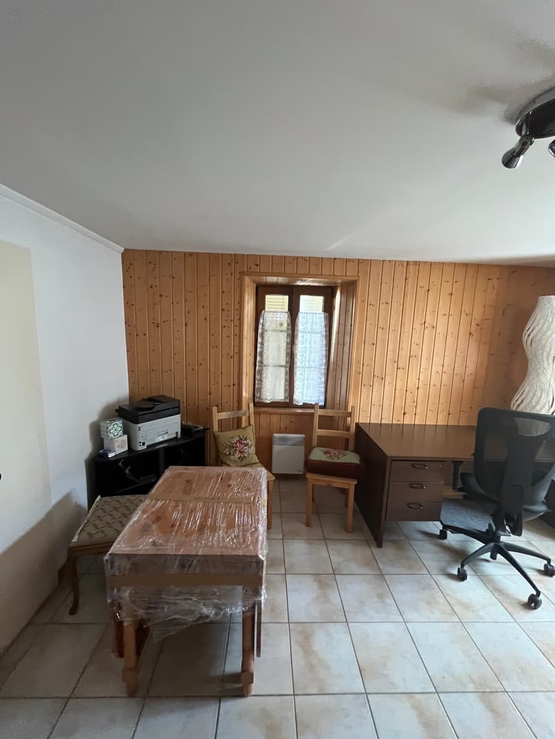 Wooden walls, white tiled floor, desk, chair, printer, window with curtains, radiator, stool, covered table