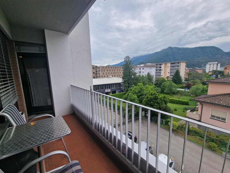 Balcony with metal railing, table, chairs, view of the street and mountains