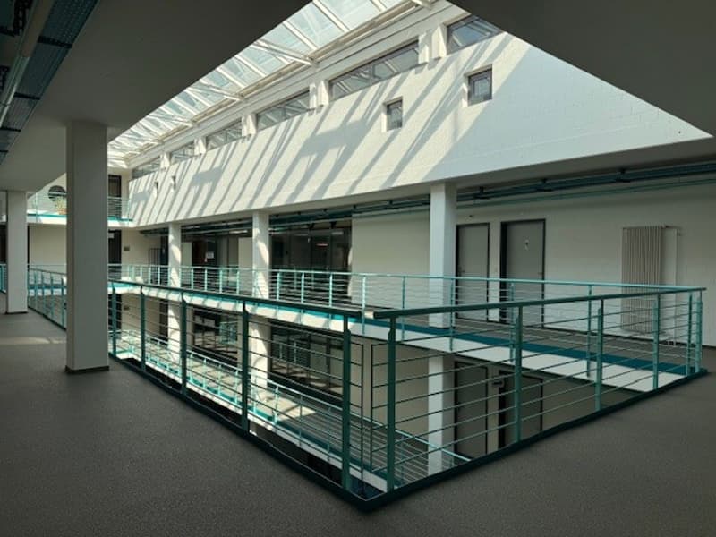 Two-story building, metal railing, glass roof, carpeted floor, large windows