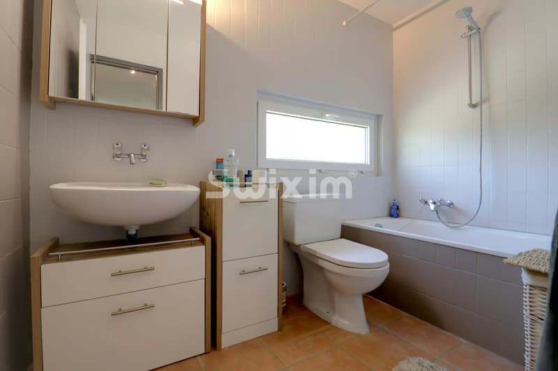 Salle de bain lumineuse avec baignoire, lavabo et WC dans une ambiance moderne.