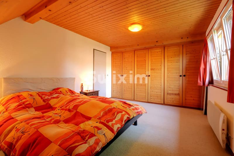 Chambre spacieuse avec plafond en bois et grand rangement intégré.