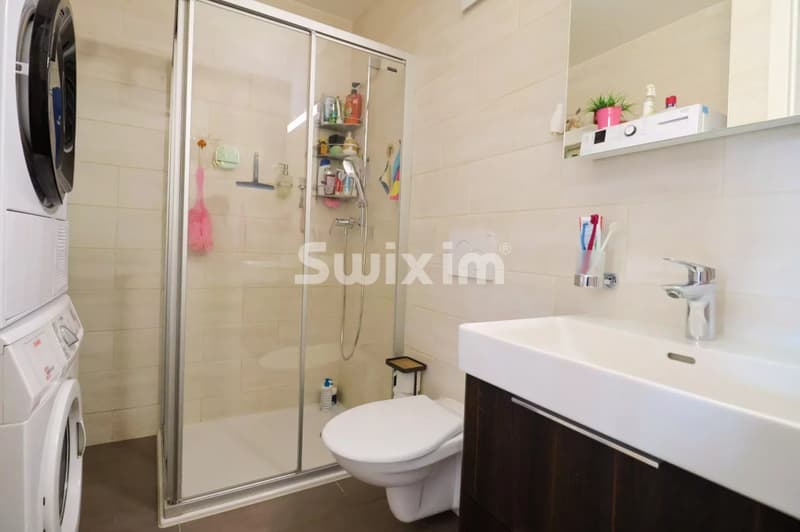 Salle de bain moderne avec douche en verre, lavabo élégant et espace de rangement pratique.