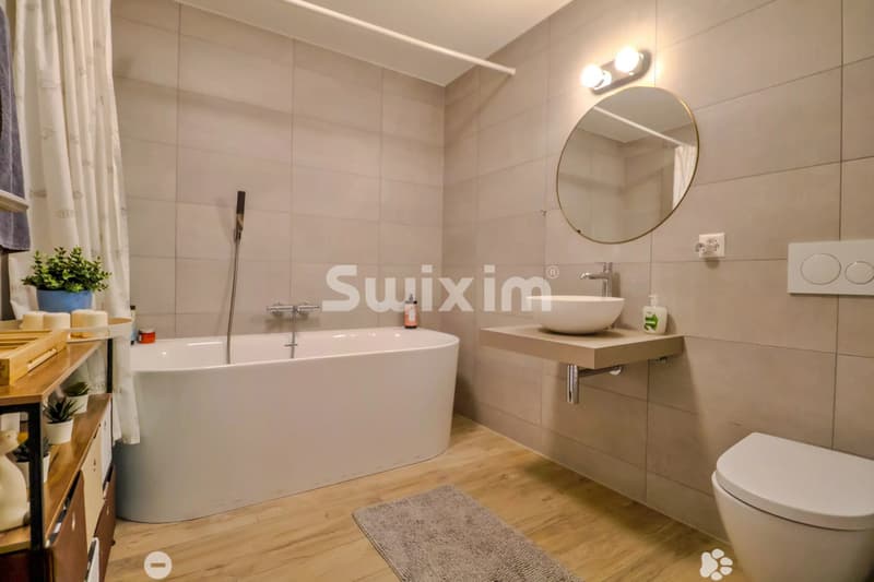 Salle de bain moderne avec baignoire et lavabo suspendu.