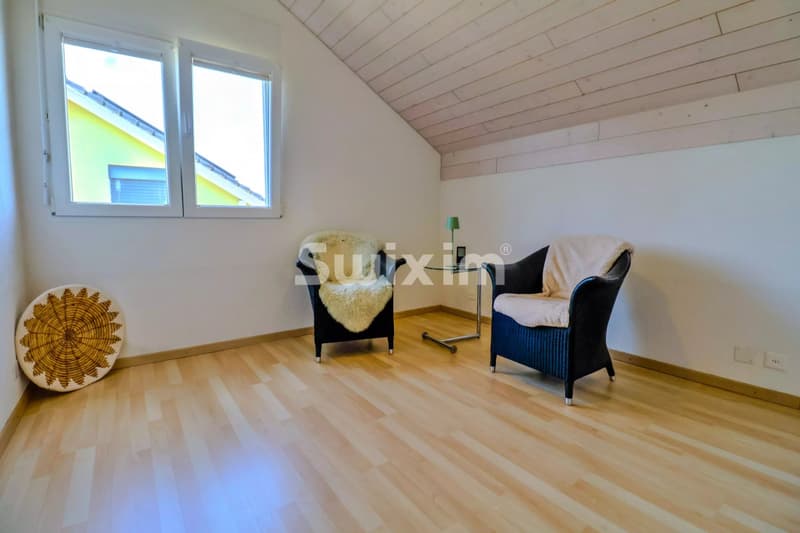 Salon lumineux avec deux fauteuils confortables et un sol en bois chaleureux.
