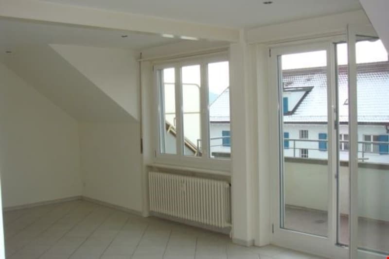 empty room with white tile floor, white walls, large windows, balcony