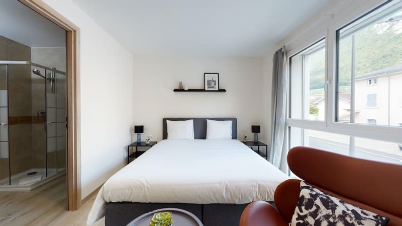 queen bed, two nightstands, chair, open shower, large window