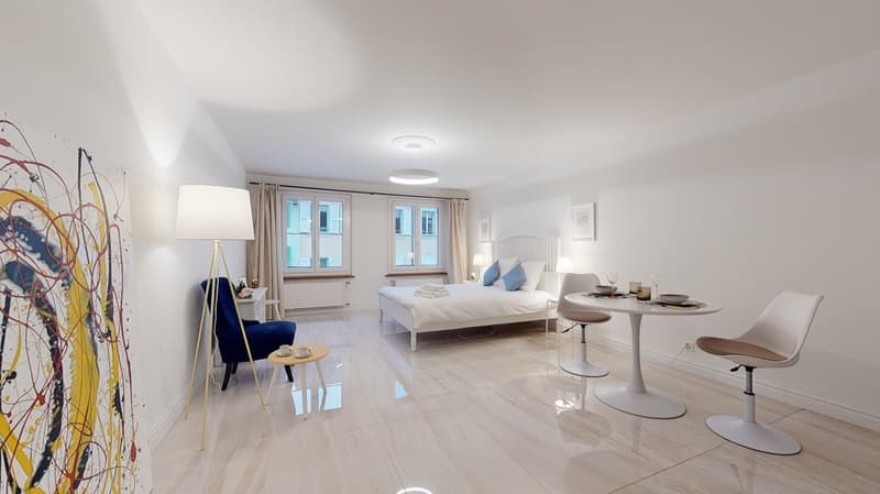 Bedroom with bed, side tables, lamps, table with two chairs, paintings, modern art on the wall