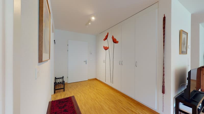 Floored hallway with wooden floor, white walls, white wooden wardrobe, shoe rack, TV on black table