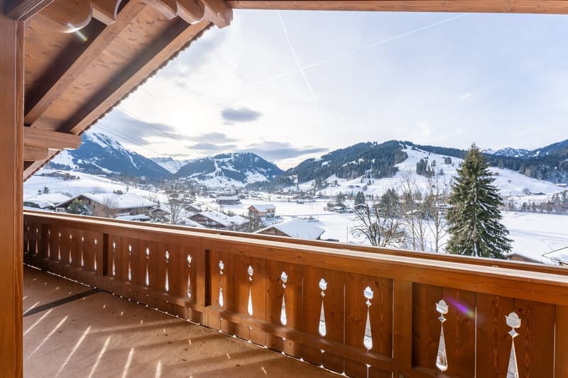 balcony with wooden railing, snowy mountain background, sunlight