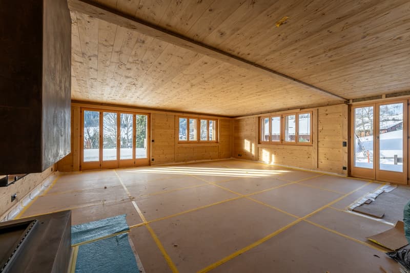 Empty room with wooden walls and floors, large glass doors and windows