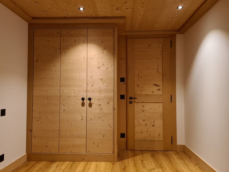 Wooden flooring, wooden door, wooden wardrobe, recessed ceiling lighting, white walls, door handles, door locks, power outlets
