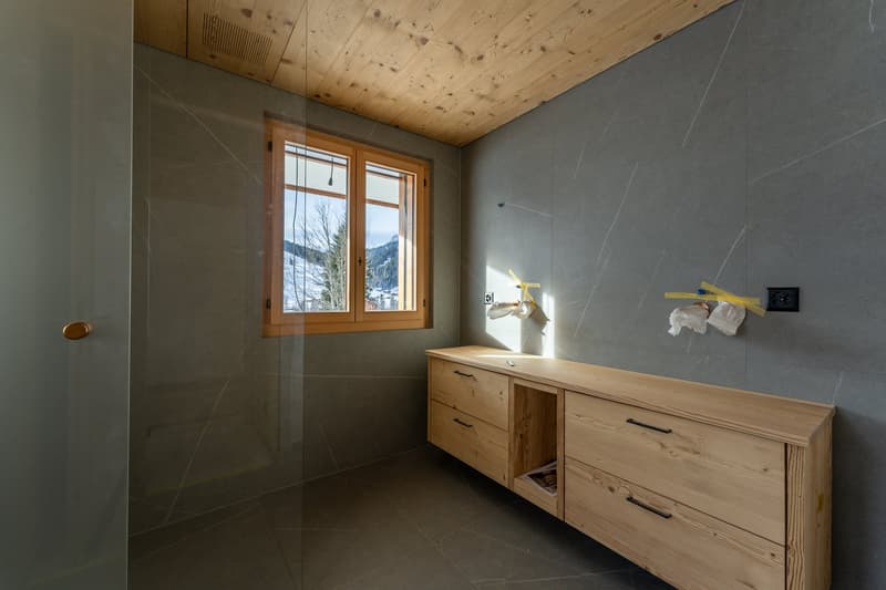 Small bathroom, wooden cabinets, gray walls, wooden ceiling, large window, window sill