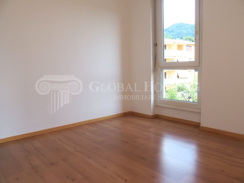 Empty room, wooden floor, white walls, large window with mountain view