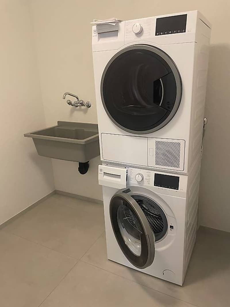 Stacked washer and dryer, single sink, tiled floor, stainless steel faucet, modern design