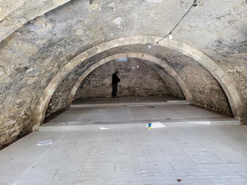 Arched ceiling, stone walls, white tile flooring, in-progress electrical wiring, arch-shaped doorways.