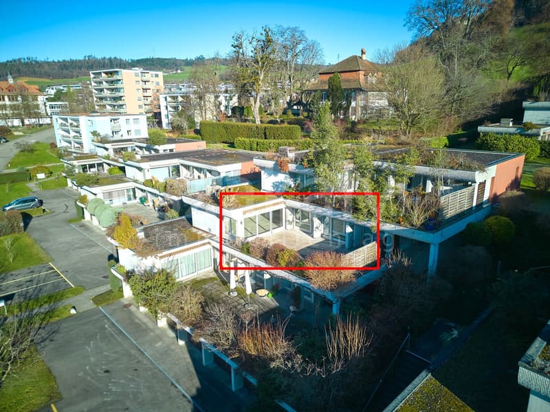 Residential apartment building with 4 floors, multiple windows, raised ground floor, green roof