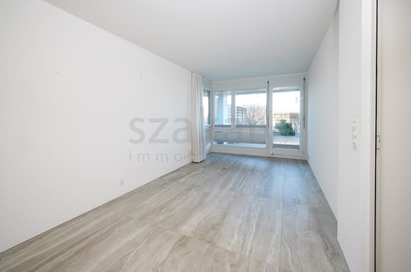 empty room with glass wall, wooden flooring, white walls, light reflection
