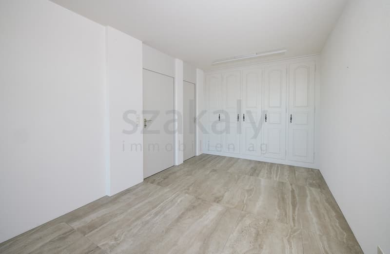 Empty room with white walls, white doors, marble flooring and cabinets