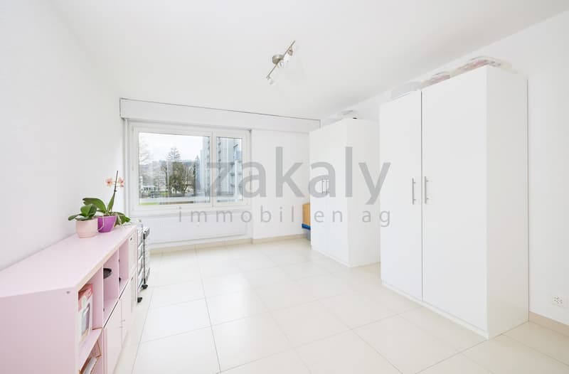 Empty room with white tiles, white walls, large window, pink shelf with plants, white wardrobes