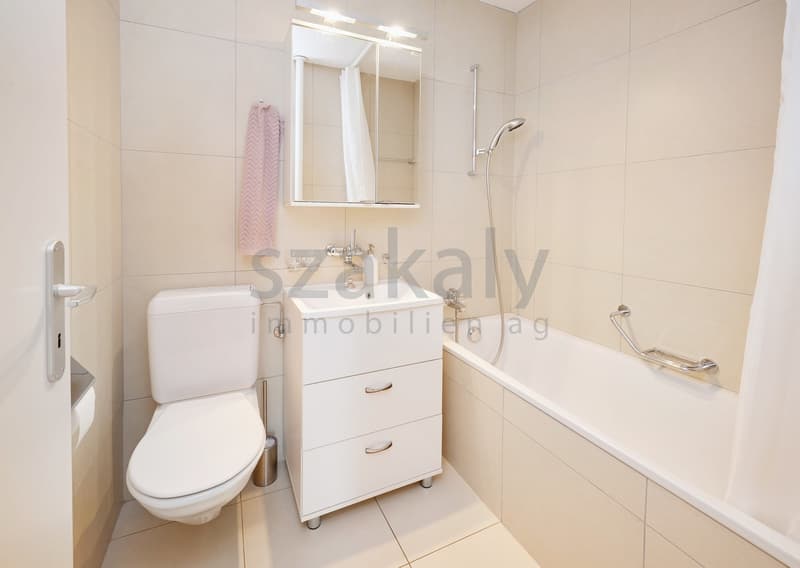 Bathroom with white tiles, white toilet, white sink, bathtub, shower head, mirror, towel