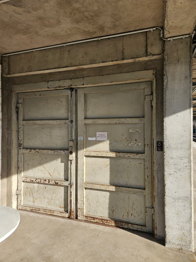 Large industrial double door with rust, concrete walls, small white round table