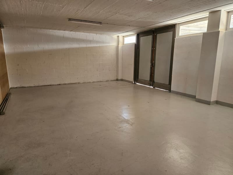 An empty room with white brick walls and a white ceiling, two windows, a glass door and concrete flooring.