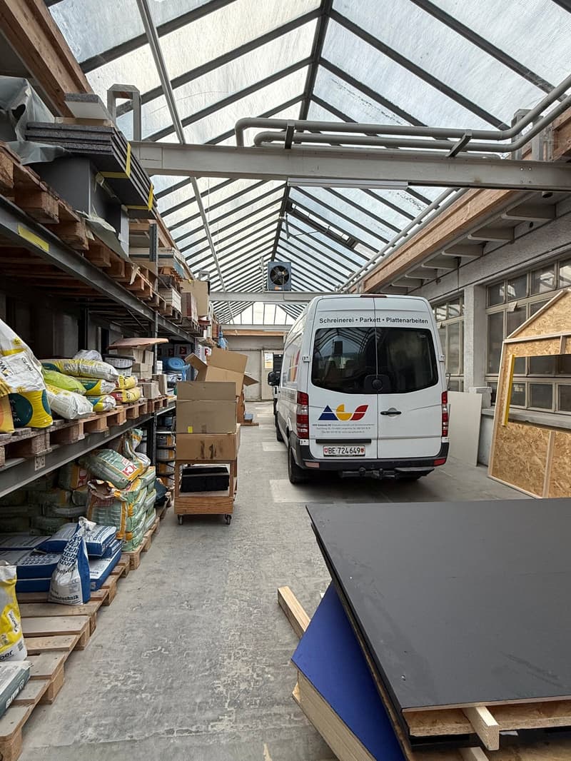 large warehouse with glass roof, pallet racks, delivery van parked, materials and products stored, wooden boxes, cardboard boxes