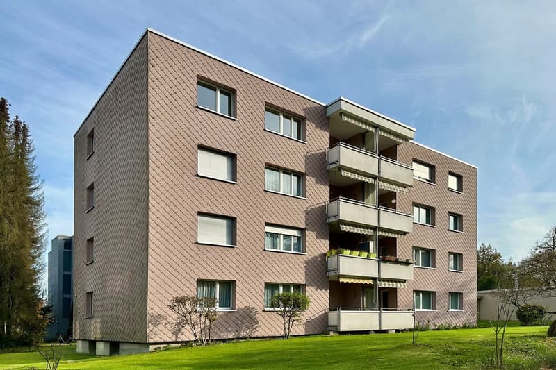 5 story building, brown exterior, multiple balconies, windows, green lawn