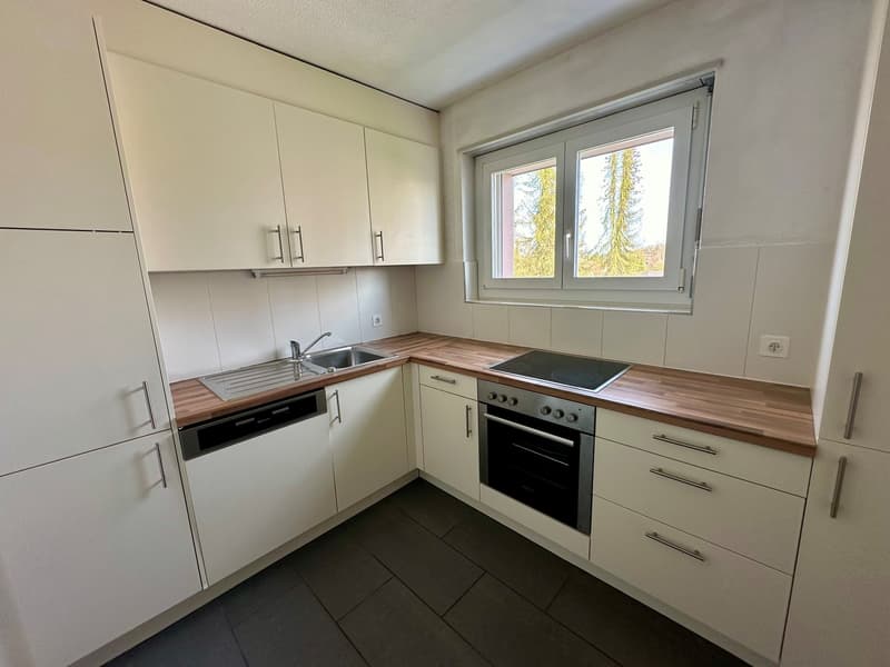 modern kitchen with white cabinets, wooden countertops, stainless steel sink, dishwasher, gas stove, oven, window