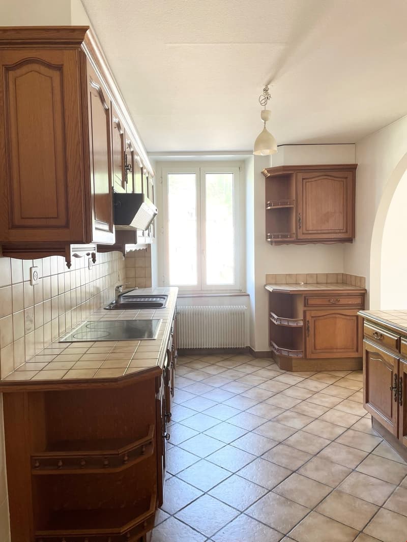 kitchen with sink, faucet, cooker, wooden cabinets, stove, wooden window, heater, tiled floors, tiled wall