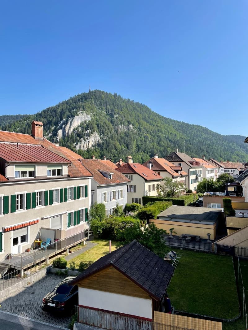 Multiple buildings, mountain range, large lawns, street, cars