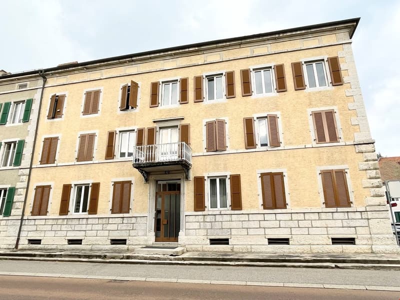 Yellow exterior, beige windows, stone base, brown shutters, balcony, wooden door