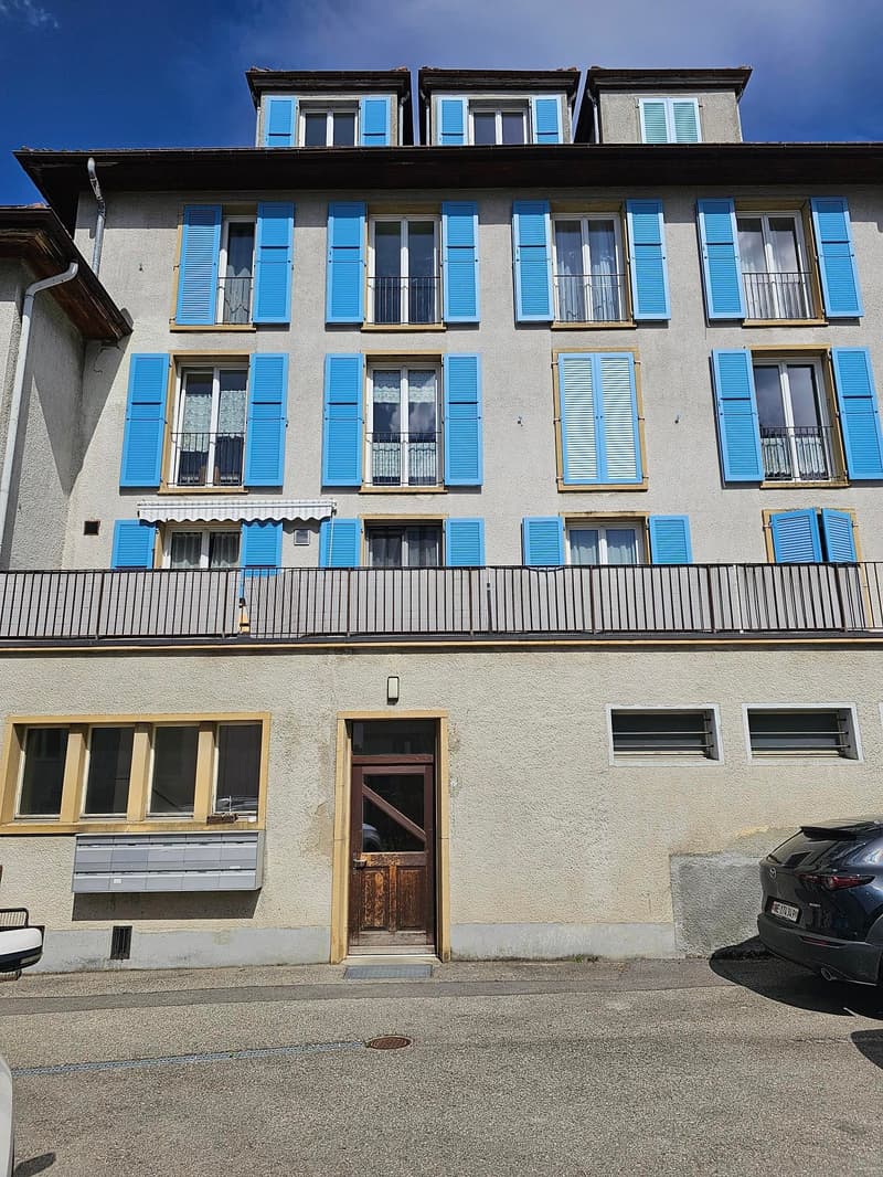 3 story building, blue shutters, balcony, wooden door, mailboxes