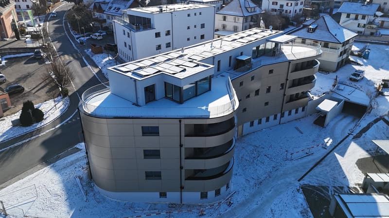 curved modern building, multi-story, glass windows, solar panels, terrace