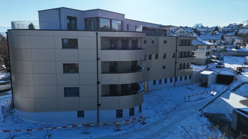 New building, curved facade, several floors with balconies, snowy surroundings