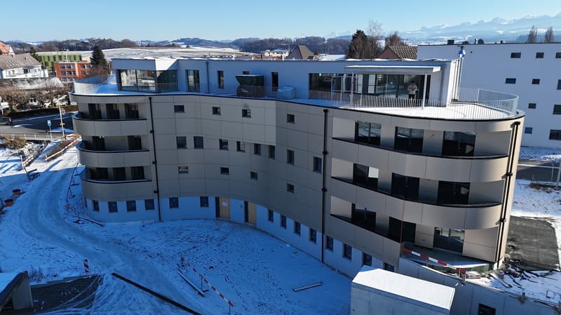 modern curved building, balcony on each level, glass facades, multiple floors, snow around