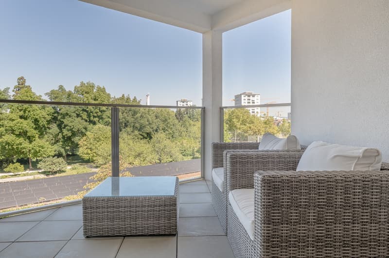 Glass railing, two rattan couch sets with white cushions, glass coffee table, tile floor