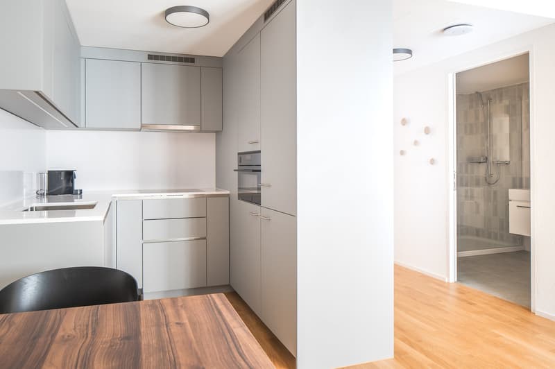 kitchen area with oven, sink, faucet, wooden dining table, white cabinets, wooden floors