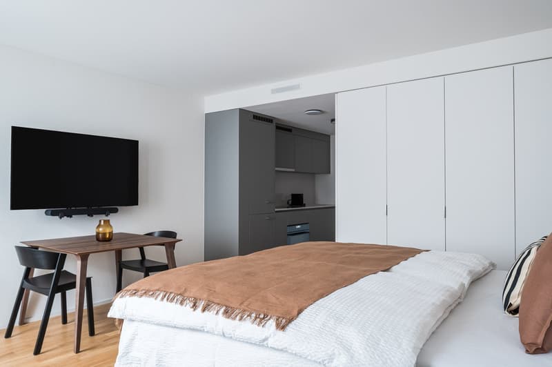 Bed, television, table, cabinets, wooden floor