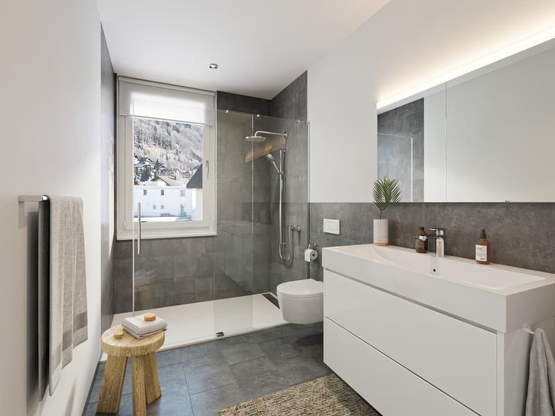 Modern bathroom with white cabinetry, large glass shower, white tiled floor, white fixtures, wall-mounted towel rack, large mirror, gray walls, large window.