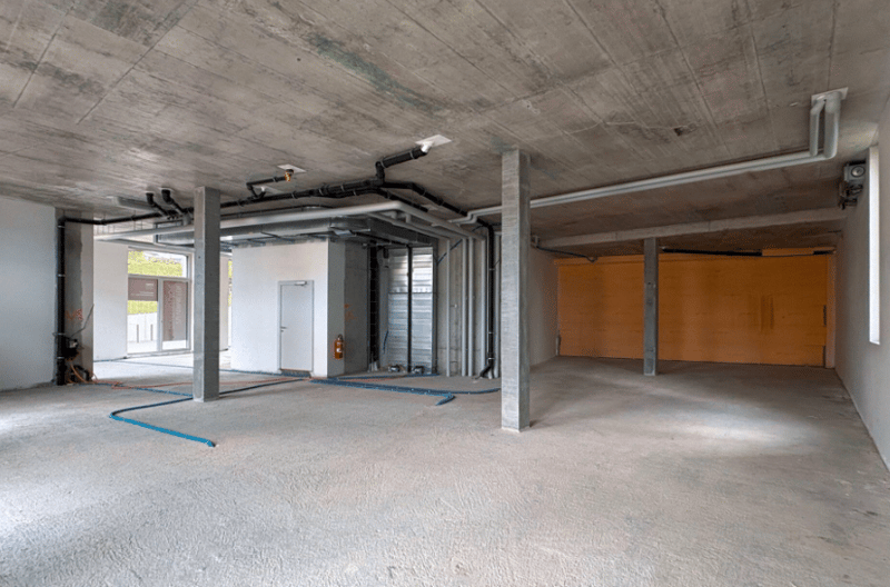 Empty basement room with unfinished design, exposed ceiling, and visible utilities