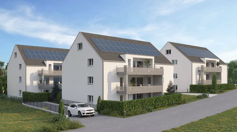 3-story apartment building with white exterior, slanted roofs, and solar panels on the roofs. The building has balconies and a parking area in front.