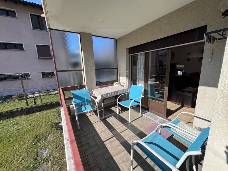 Balcony with table and chairs, glass doors, tiled floor, view of a grassy area