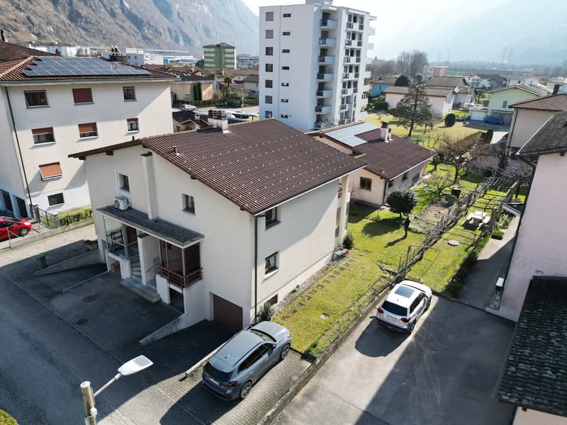 3 story house, brown roof, solar panels, garage, 2 cars parked in front