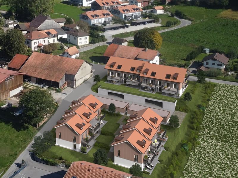 Aerial view of a residential complex with multiple multi-story buildings, red tile roofs, and balconies. The buildings are surrounded by green lawns and trees, with a winding road leading through the complex.