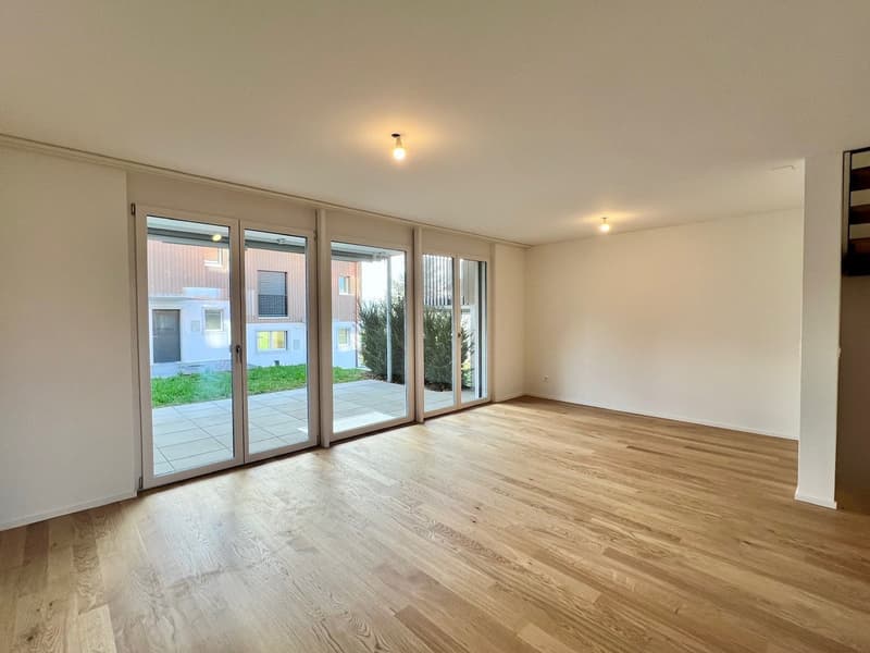 Empty room with large windows leading to balcony, hardwood floor