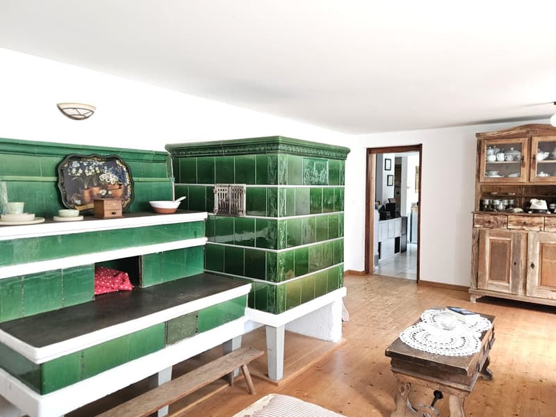 green tiled fireplace, wooden bench, wooden table, wooden cabinet, white ceiling, wooden floor