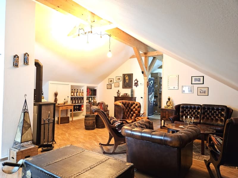 wooden floor, wooden beams, fireplace, leather couches, wooden table, shelves with bottles, framed pictures on the wall