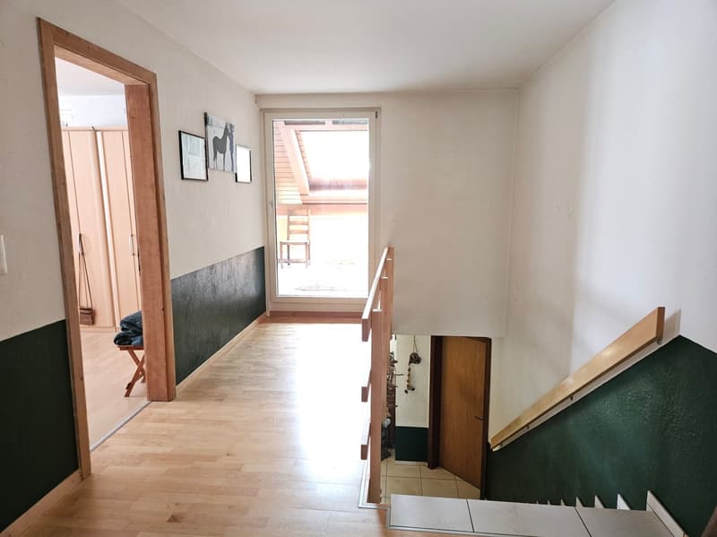 wooden floor, white walls, green and white wall stripes, wooden handrail, glass door, wooden chair, picture frames, mirror, wooden cabinet